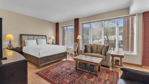 Una habitación de hotel con una cama, un sofá, una mesita y una silla.