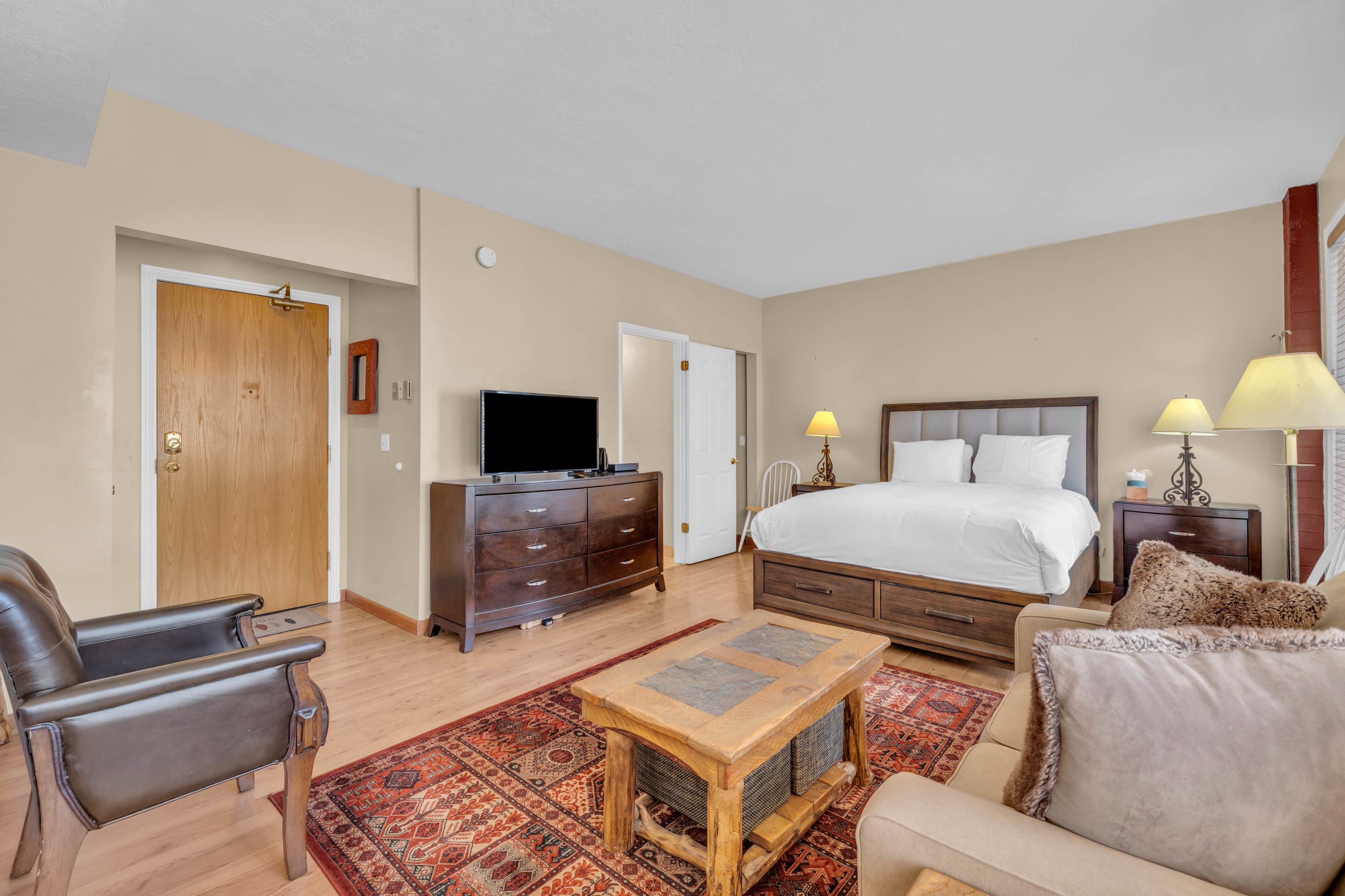 Ein Hotelzimmer mit einem Bett, einem Schreibtisch, einem Fernseher, einem Sessel und einer Couch.