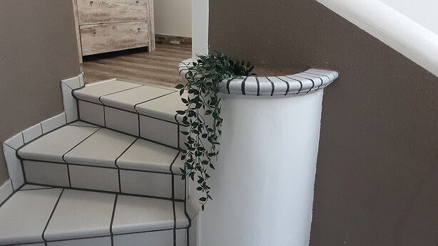 A staircase with white tiled steps and a planter with green foliage on the right side.