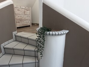 A staircase with white tiled steps and a planter with green foliage on the right side. - Holiday Home 'Garten Der Ruhe' with Balcony and Wi-Fi (Osterbuch)