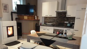 A modern kitchen with a built-in stove, a dining area with a table and chairs, and a flat-screen TV mounted above the stove.