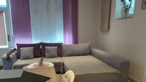 A compact living space with a sofa, a small dining table, and a chair.