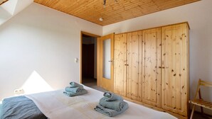 Een slaapkamer met een bed, een houten garderobe en een raam.