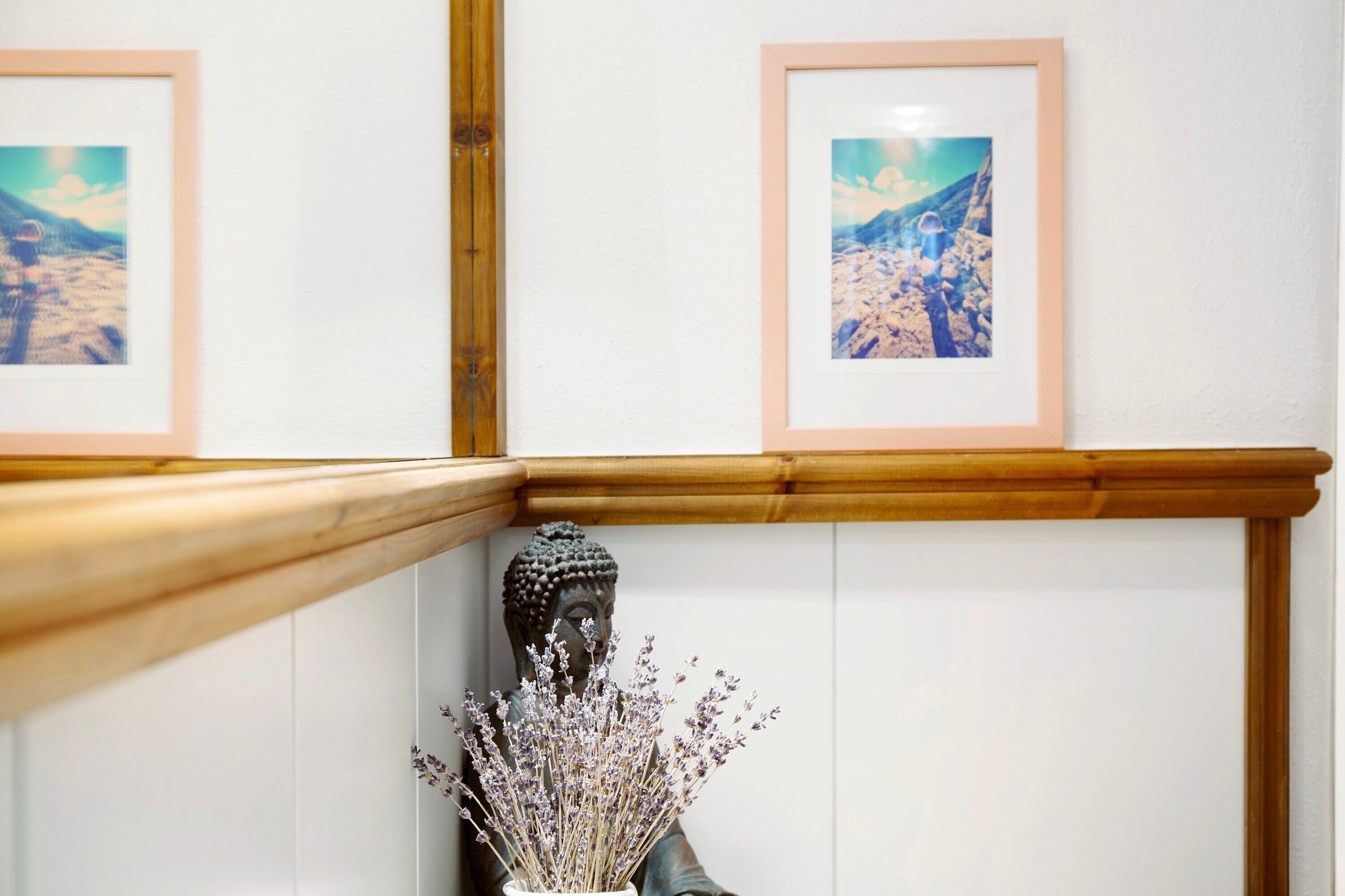 Una escalera con barandillas de madera, una estatua de Buda y dos cuadros en la pared.