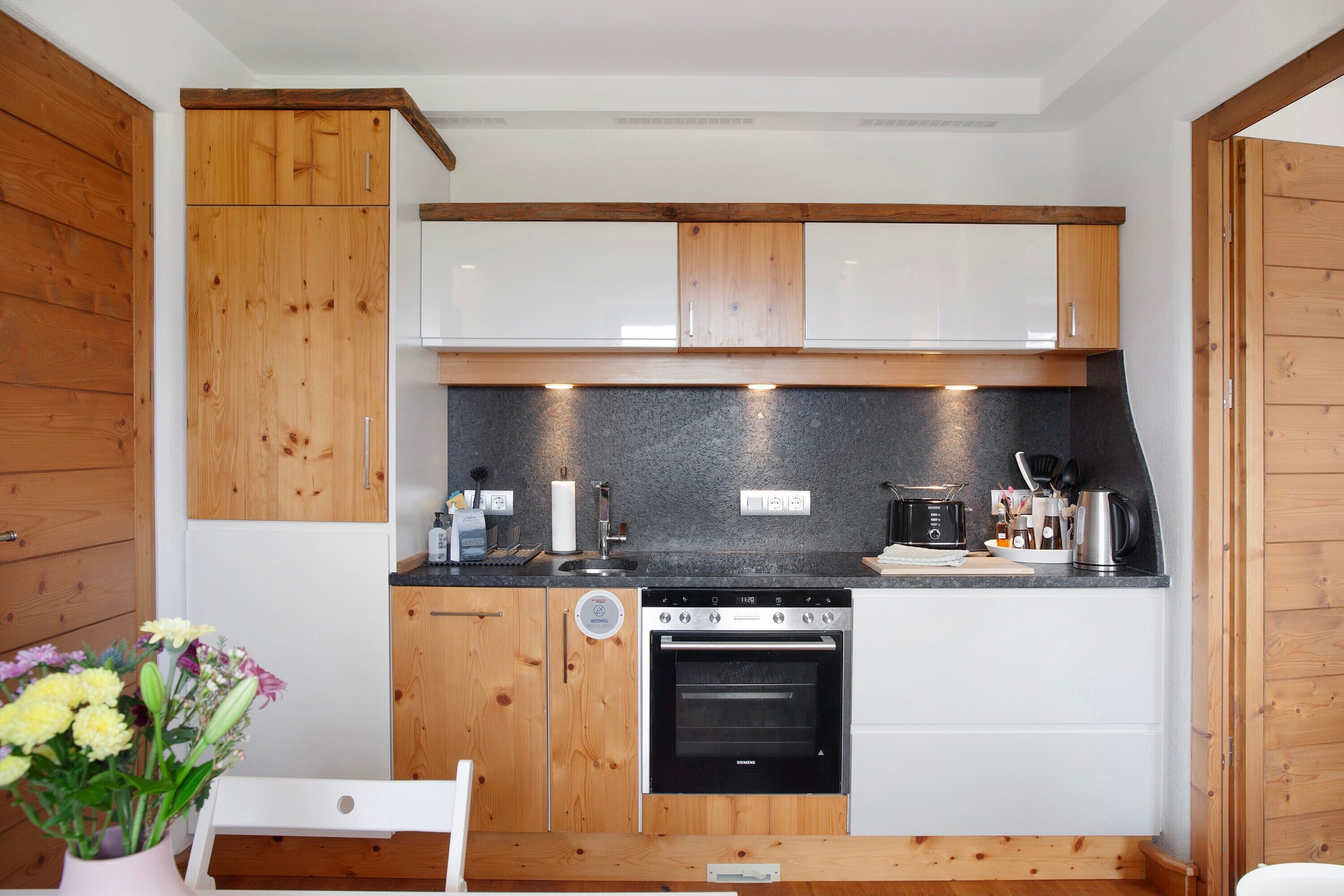 A compact kitchen with wooden cabinets, a built-in oven, and a countertop with various appliances.