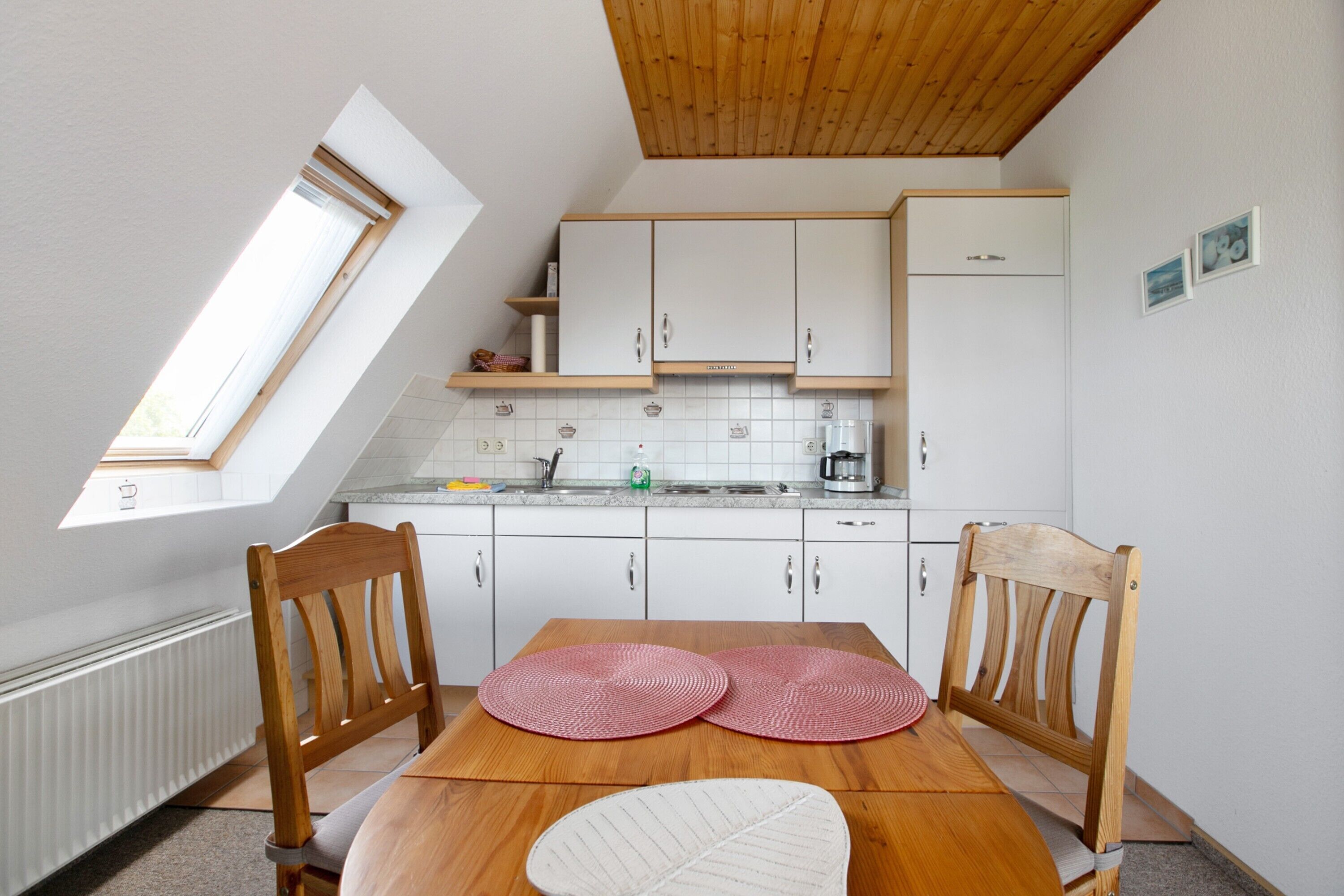 A kitchen with white cabinets, a wooden table, and a window.