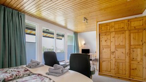 A bedroom with a bed, two chairs, a wooden wardrobe, and a window with curtains. - Apartment 'Balkonwohnung' with Shared Garden, Balcony and Wi-Fi (Westerdeichstrich)