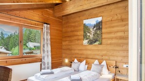 A wooden cabin bedroom with two beds, a window with curtains, a wall-mounted picture, and a nightstand. - 'Blockhaus Sonnenspitz' holiday flat with mountain views, communal garden and WLAN (Leutasch)