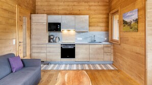 A compact kitchen with wooden walls, a built-in microwave, a stove, and a sink. - 'Blockhaus Sonnenspitz' holiday flat with mountain views, communal garden and WLAN (Leutasch)