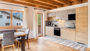 A modern kitchen with wooden cabinets, a built-in oven, and a dining area with a table and chairs.