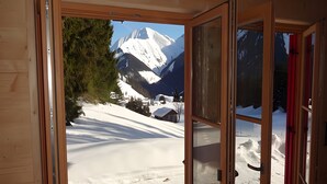 Uma porta de madeira que dá para uma vista de montanha nevada.