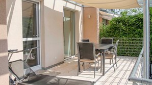 Un balcon avec une table et des chaises, un abri pour voiture et une porte vitrée.