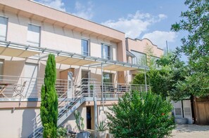 Un edificio residencial con un espacio exterior techado, una escalera y diversas plantas.