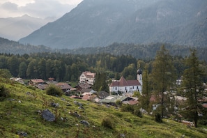 A mountainous village with traditional houses, a church, and a prominent building with a red roof. - Studio Apartment 'Mini Apartment 2' with Mountain View, Shared Garden and Wi-Fi (Mittenwald)