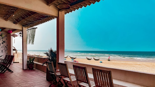 A beachside terrace with wooden chairs and a view of the ocean. - Jeju Beach Front Villa (Da Nang)