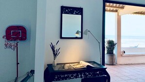 A room with a basketball hoop, a desk with a lamp, a mirror, and a view of the sea. - Jeju Beach Front Villa (Da Nang)