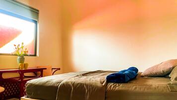 Un dormitorio con cama, ventana con vistas, escritorio y una silla.