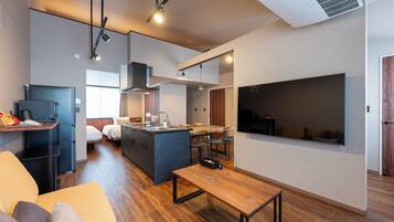 A modern kitchen with a central island, a dining area with a wooden table, and a living space with a sofa.