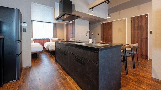 Una cocina moderna con una isla central, electrodomésticos integrados y una zona de comedor con taburetes de bar.