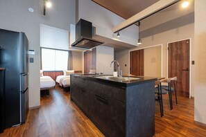 Una cocina moderna con una isla central, electrodomésticos integrados y una zona de comedor con taburetes de bar.