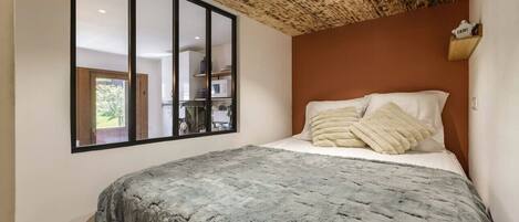 Un dormitorio con una cama grande, techo de madera, una ventana y vistas al exterior.