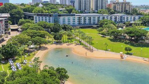 A hotel with a large pool, surrounded by lush greenery and a clear view of the city skyline. - Darwin Waterfront Penthouse  (Darwin)
