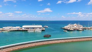 A marina with boats docked, a large white building, and a clear blue sky. - Darwin Waterfront Penthouse  (Darwin)
