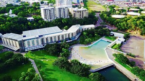 An aerial view of a modern urban area with high-rise buildings, a large open green space, and a waterfront. - Darwin Waterfront Penthouse  (Darwin)