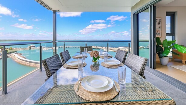 A dining table with chairs, a glass top, and a view of the ocean. - Darwin Waterfront Penthouse  (Darwin)