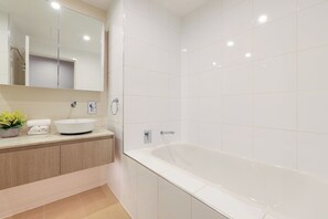Ein modernes Badezimmer mit einer großen Badewanne, einem Waschbecken und einem Spiegel.