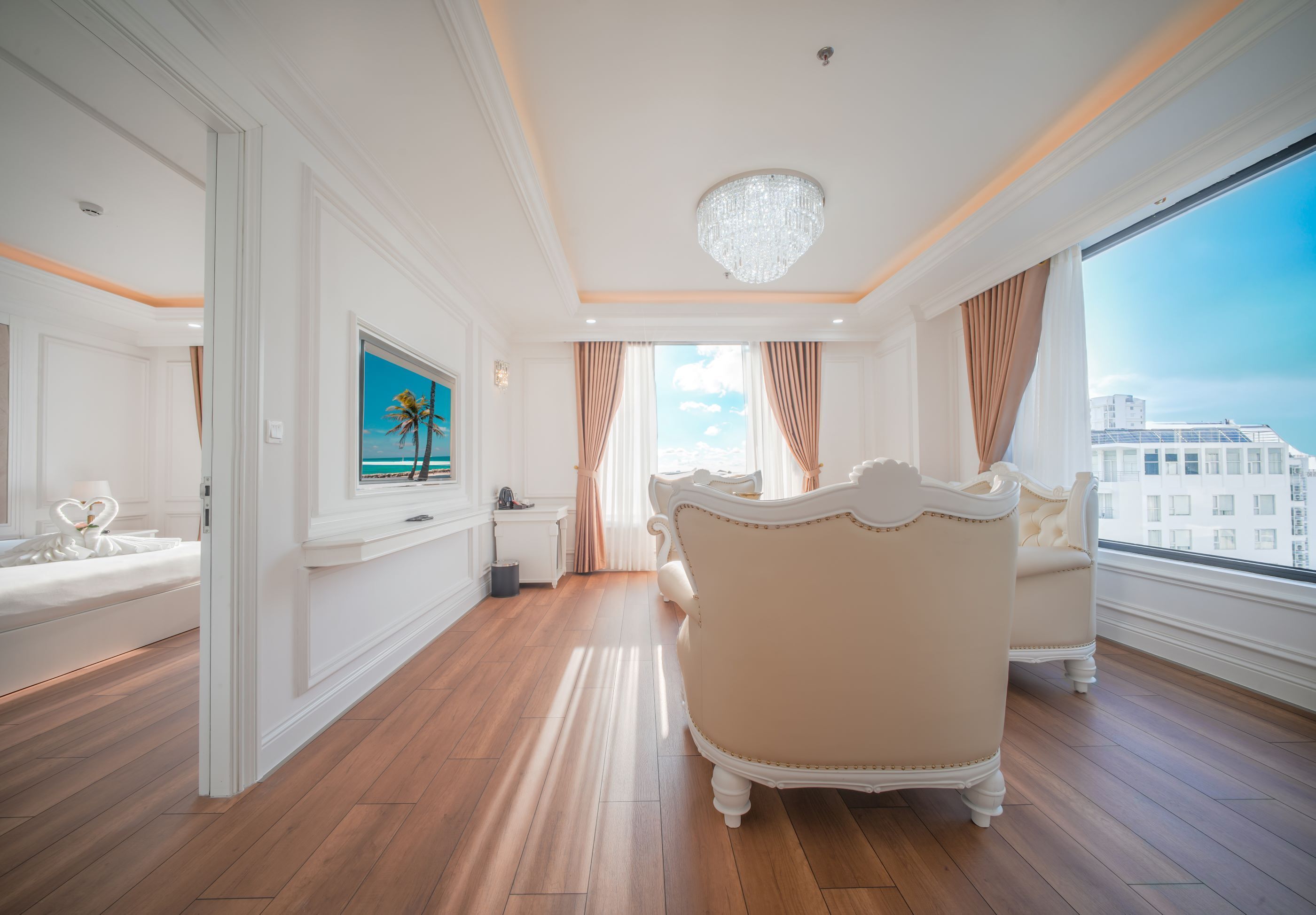 A spacious room with a large bed, a chandelier, and a view of the city.