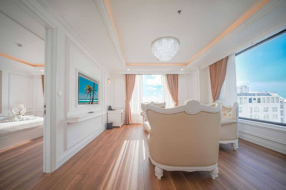 A spacious room with a large bed, a chandelier, and a view of the city.