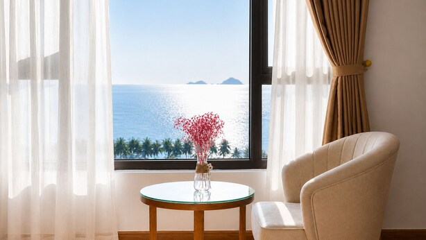 A room with a view of the sea, a round glass table with a vase, and a beige armchair. - Sea Soul Hotel (Nha Trang)