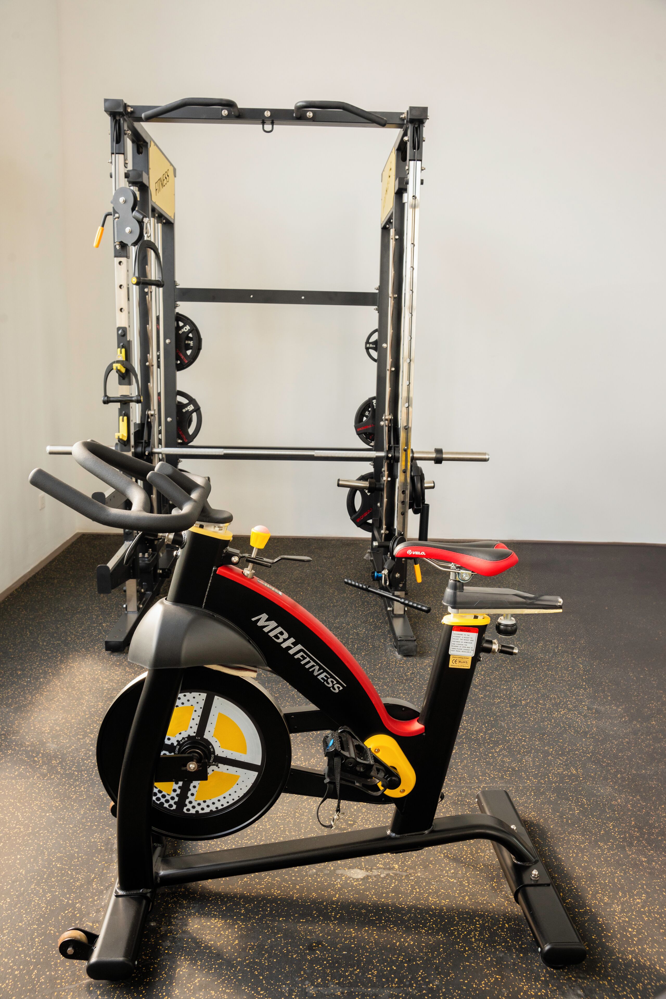 A stationary bike with a weight stack and a barbell rack.