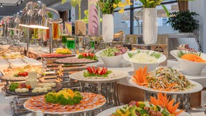 A buffet with various food items and decorative flowers. - Sea Soul Hotel (Nha Trang)