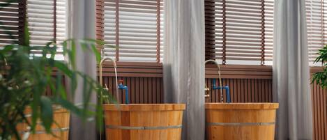 A greenhouse with wooden barrels, a water fountain, and a pebbled floor.