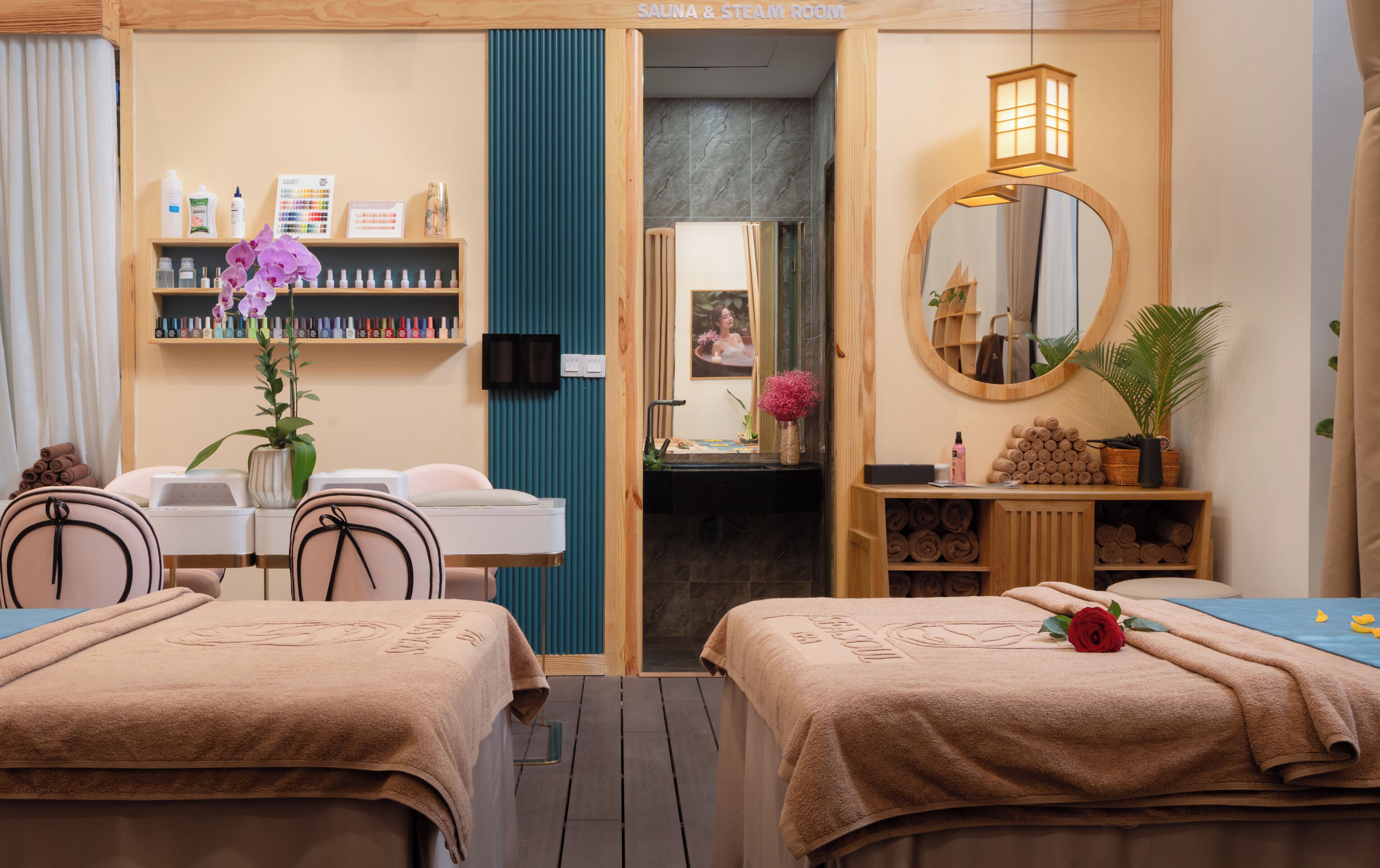 Une salle de spa équipée de deux lits, d’une coiffeuse avec des articles de toilette, d’un miroir et d’un espace sauna.