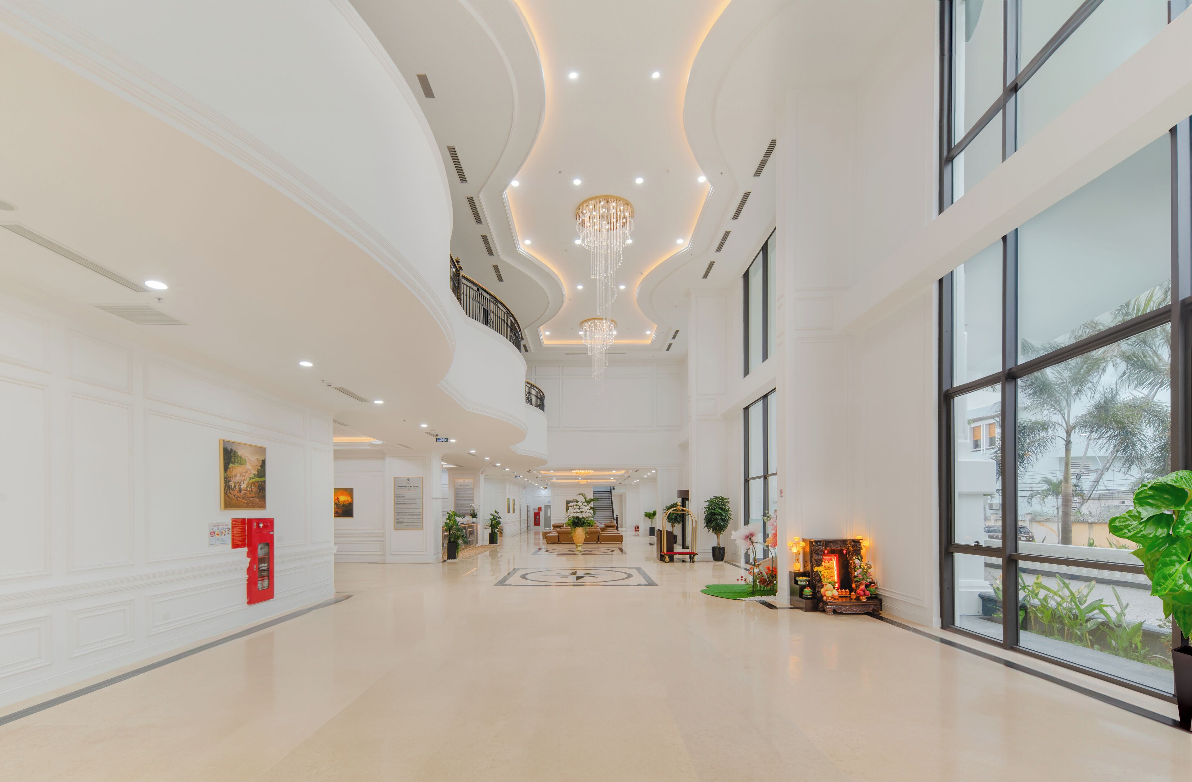 A spacious lobby with a high ceiling, large windows, and a central chandelier.