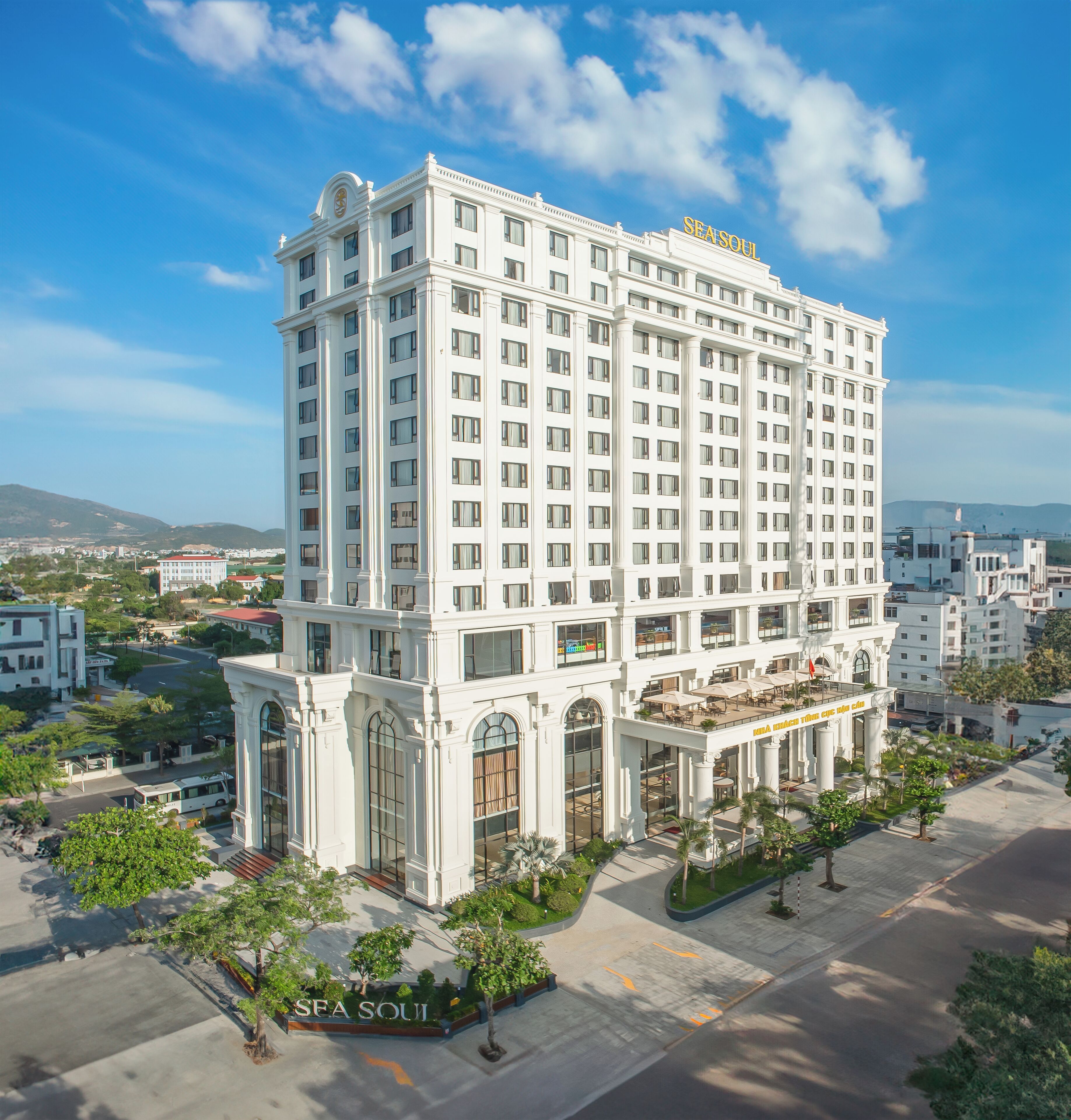 A multi-story hotel with a prominent entrance, a rooftop terrace, and a clear view of the surrounding cityscape.