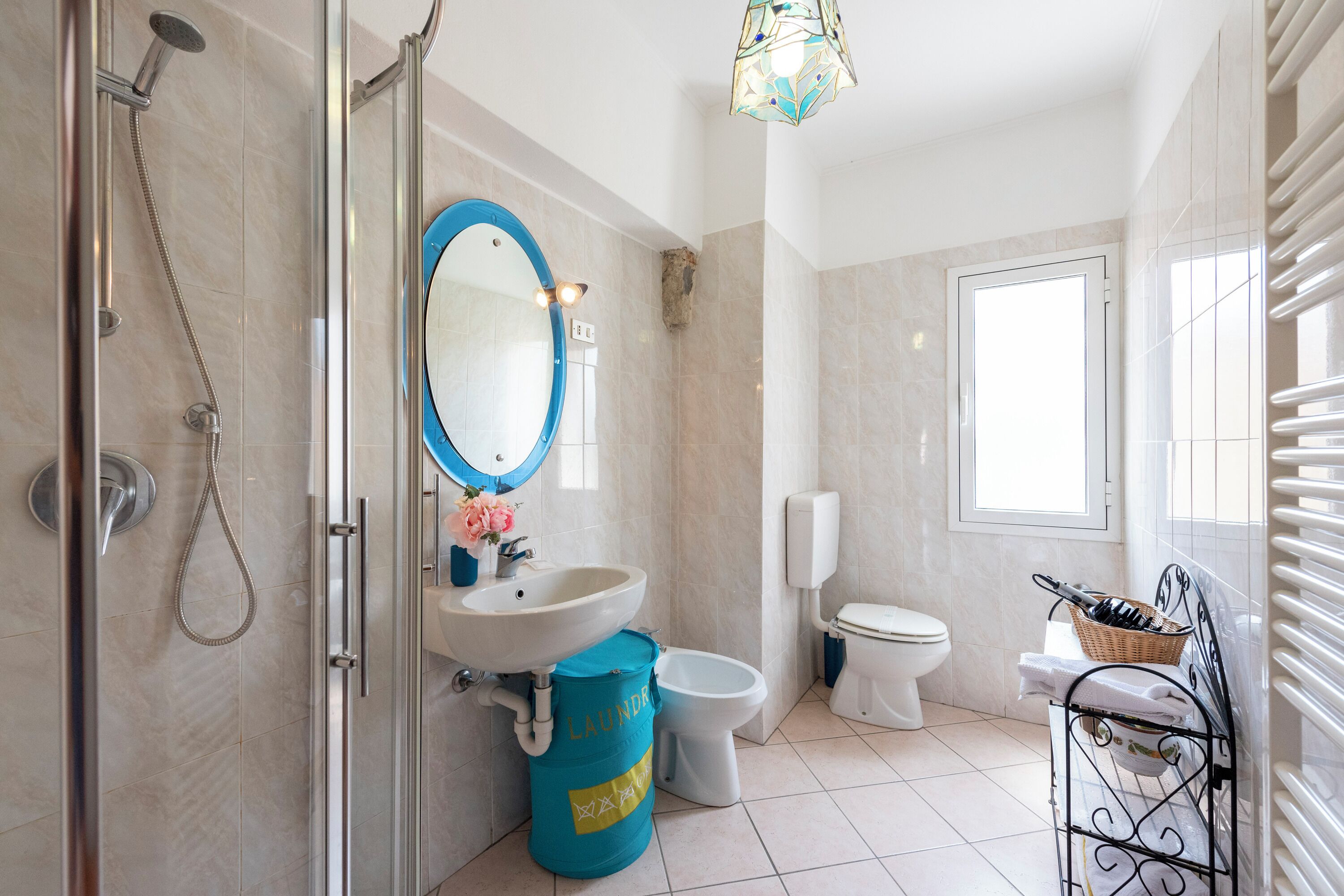 Un baño con ducha, lavamanos, inodoro y ventana.