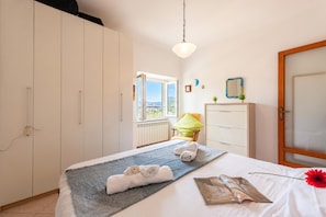 Habitación de hotel con cama, una silla, armario y vista al exterior.