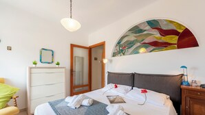 A neatly made bed with towels, a bedside lamp, and a decorative mirror. - Kimera Del Parasio Historic Apartment for 4 (Imperia)