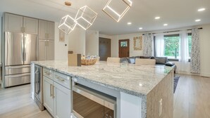 A modern kitchen with a marble countertop, stainless steel appliances, and pendant lighting. - Spacious Riverfront Delaware Home w/ Views (Delaware)