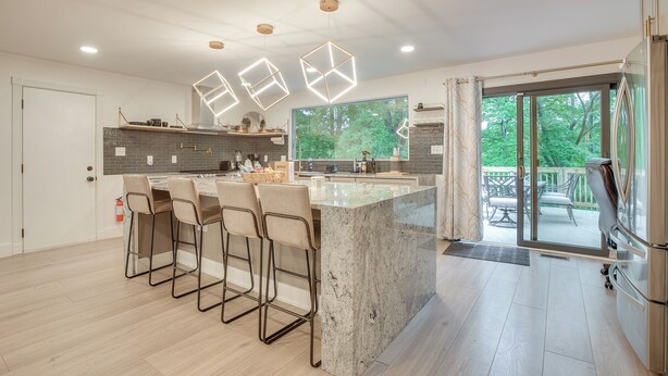 A modern kitchen with a central island, bar stools, pendant lights, and a view of the outdoors. - Spacious Riverfront Delaware Home w/ Views (Delaware)