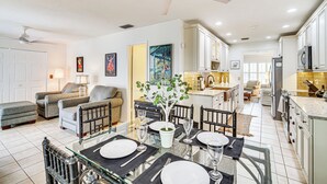 A spacious living area with a dining table set for four, a kitchen with white cabinets, and a ceiling fan. - Hobe Sound Villa w/ Screened Porch: 4 Mi to Beach (Hobe Sound)
