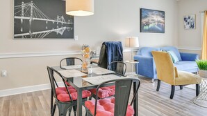 A modern living room with a dining table, chairs, a sofa, and a blue armchair.