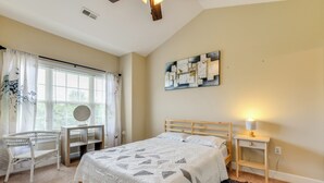 A bedroom with a bed, a desk, a chair, a rug, and a wall art piece.