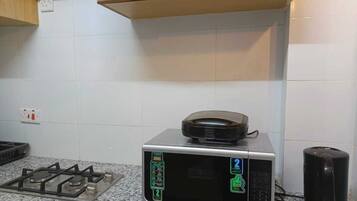 Uma cozinha com fogão a gás, micro-ondas e máquina de café.