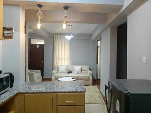 A compact living space with a kitchenette, a sofa, and a dining area. - Lux Suites Explorer Apartments Kisii (Kisii)
