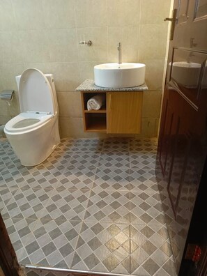 A bathroom with a toilet, a sink, and a shelf with a towel.